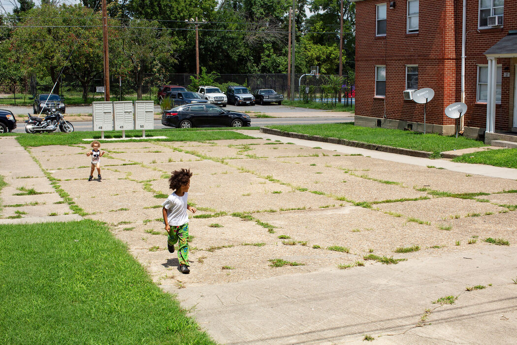 this image depicts a young child playing on a light colored asphalt surface with no tree cover for shade.